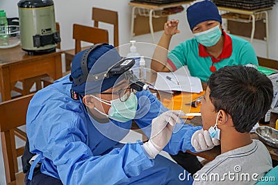 BALI/INDONESIA-MAY 28 2021: An ENT doctor is examining the ears, nose and throat of a pediatric patient. During the COVID-19 Editorial Stock Photo
