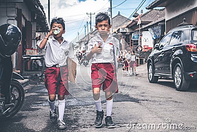 BALI, INDONESIA - MAY 23, 2018: Group of balinese schoolboys in a school uniform on the street in the village. Editorial Stock Photo