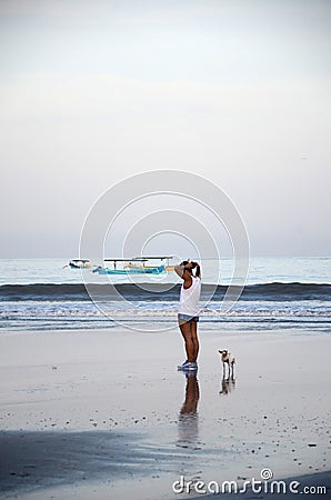 Woman with dogs walking at tropical beach in the morning in Bali, Indonesia Editorial Stock Photo