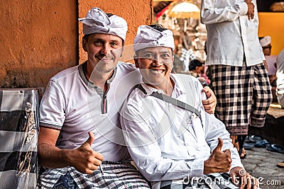 BALI, INDONESIA - SEPTEMBER 25, 2018: Balinese men with european man in traditional clothes on a big ceremony in Tirta Editorial Stock Photo