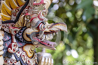 Balinese ancient colorful bird god Garuda with wings, closeup. Religious traditional statue from wood. Wooden old curved figure of Stock Photo