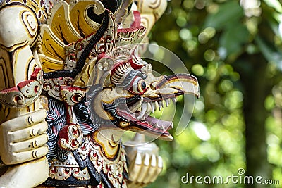 Balinese ancient colorful bird god Garuda with wings, closeup. Religious traditional statue from wood. Wooden old curved figure of Stock Photo