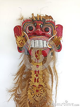 Balinese Barong Mask decoration with long blonde hair hanging on white wall background. Stock Photo