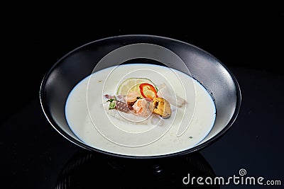 Balinese cream soup with seafood in a black plate on a dark background Stock Photo