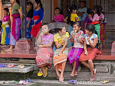 Balinese girl resting after school dances and eating ice cream. Ubud, Indonesia Editorial Stock Photo