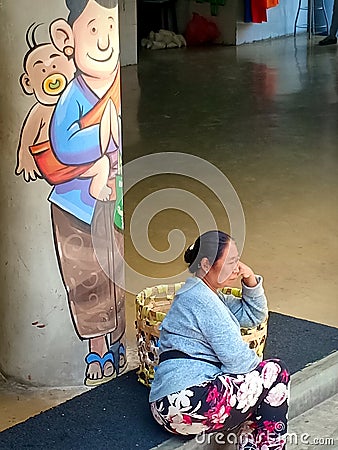 A balinese porter woman sitting on the stairs Editorial Stock Photo