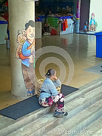 A balinese porter woman sitting on the stairs Editorial Stock Photo