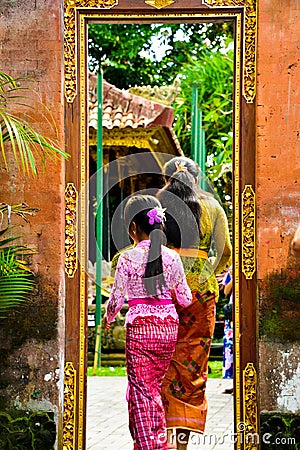 A Balinese teenage little school girl wearing traditional local clothing entering a sacred temple Stock Photo