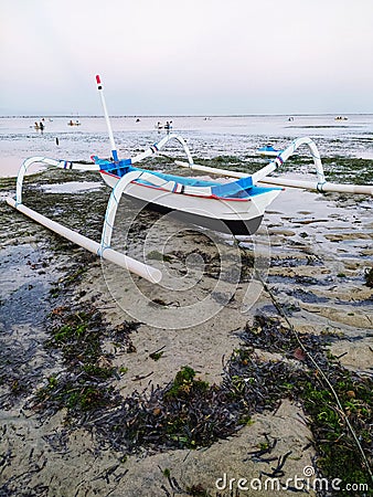Balinese traditional fishing boat with wood material leaning on the beach Stock Photo