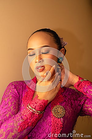 Balinese Women showing their green earrings while wearing a pink traditional dress Stock Photo