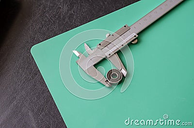 Ball bearing and vernier caliper on a black and turquoise background Stock Photo