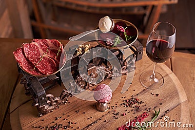 A ball of ice cream from beets and meat in an old ice-cream bowl on the background of steaks seasoned beef on vintage scales Stock Photo