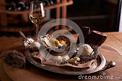 A ball of ice cream in a vintage metal ice-cream bowl on a wooden background with an assortment of cheeses in the background Stock Photo