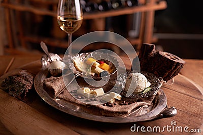 A ball of ice cream in a vintage metal ice-cream bowl on a wooden background with an assortment of cheeses in the background Stock Photo