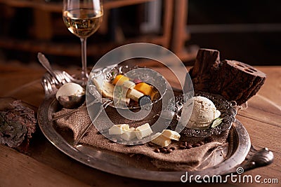 A ball of ice cream in a vintage metal ice-cream bowl on a wooden background with an assortment of cheeses in the background Stock Photo