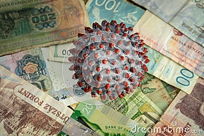 A painted ball like a SARS-CoV-2 virion on the middle of many banknotes from different countries Stock Photo