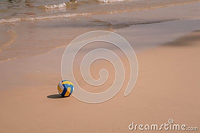 Ball at sandy beach close to seashore line. Blue yellow white stripes Stock Photo