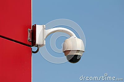Ball shaped rotatable waterproof security camera CCTV mounted on side wall of red office building Stock Photo