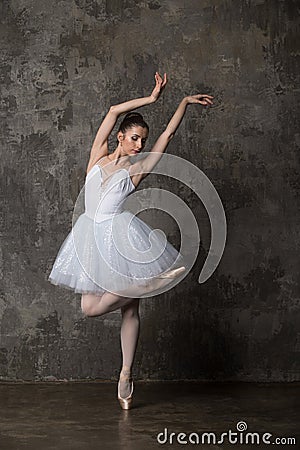 Ballerina dancing against gray loft background in studio Stock Photo