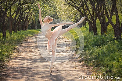 Ballerina dancing outdoors in green forest landscape at sunset Stock Photo