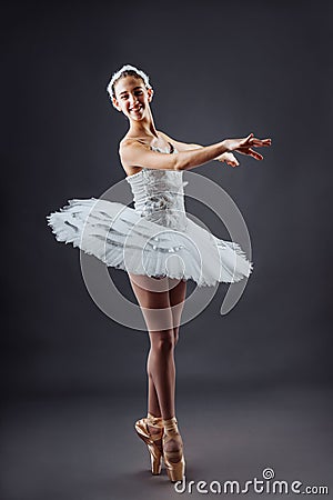 Ballerina dancing in white dress. Color photo. Graceful ballet dancer or classic ballerina dancing on grey studio Stock Photo