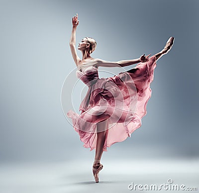 Ballerina in Pink Chiffon Dress jumping Split. Ballet Dancer in Silk Gown Pointe Shoes. Graceful Woman in Tutu Skirt dancing over Stock Photo