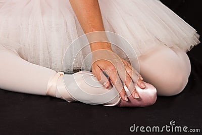 Ballerina sit down on floor to put on slippers with hands for pe Stock Photo