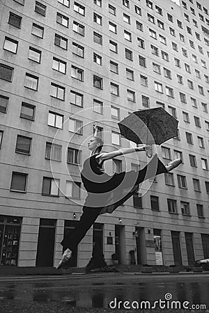 Ballerina with umbrella on city street under water drops Stock Photo