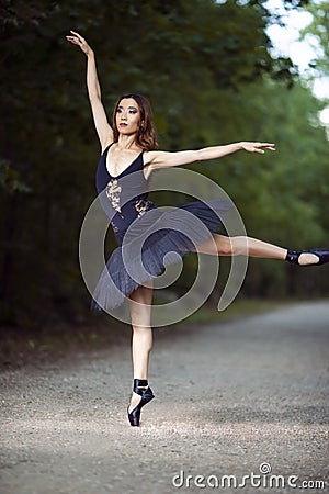 Ballet Concepts. Professional Japanese Female Ballet Dancer Posing in Black Tutu Against Forest Background And Beautifully Lifted Stock Photo