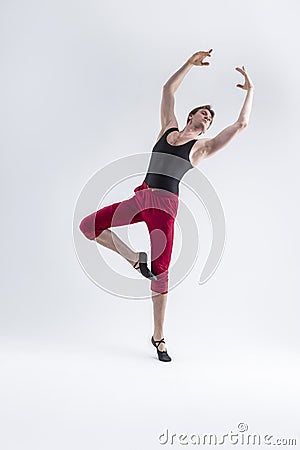 Ballet Ideas. Modern Ballet of Flexible Athletic Man Posing in Red Tights in Ballanced Dance Pose With Hands Lifted in Studio on Stock Photo