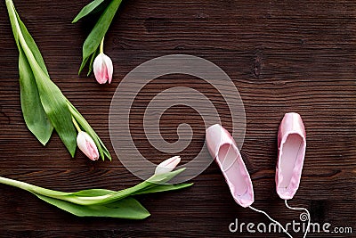 Ballet pointe shoes near spring tulips on dark wooden background top view copy space Stock Photo