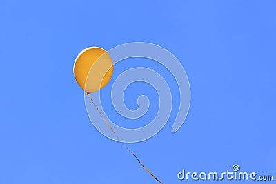 Yellow balloon flying in blue sky Stock Photo