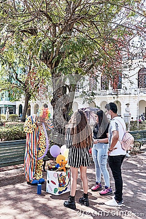 Balloon seller in coloful clown costume in central park Vidal, Santa Clara, Cuba Editorial Stock Photo
