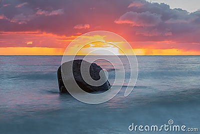 Baltic sea with big stone at twilight with dramatic clouds Stock Photo