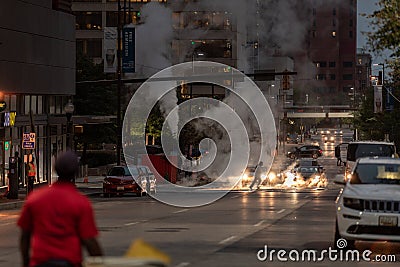 Baltimore Downtown with Late Evening Traffic in Background. People Crossing Street. Pipe Vapour Steam in Background Editorial Stock Photo