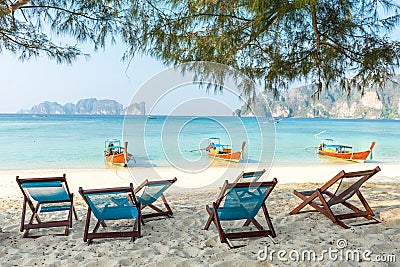 Bamboo beach chairs and traditional long-tail boats Stock Photo