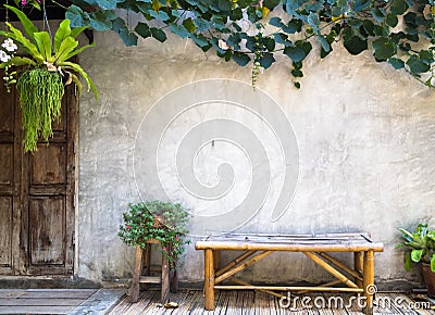 Bamboo bench with decorative plant on concrete wall background Stock Photo