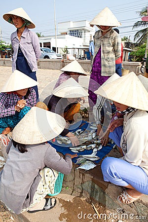 Bamboo hat Vietnamese women choose fish to sell in market Editorial Stock Photo