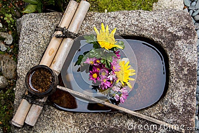 Bamboo ladle on a stone basin filled with a flower arrangement in Kyoto Japan Stock Photo