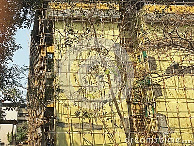 Bamboo Scaffolding on twenty-five-year-old four-storey building gating structural Repair work going on Stock Photo