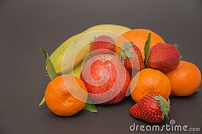 Banana, apple, orange,strawberries and Three tangerine with leaves on a beautiful gray background, beautiful colors and compositi Stock Photo