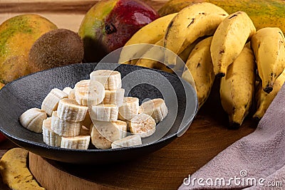 Banana bunch, sliced bananas in bowl and on wooden board Stock Photo