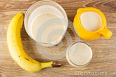 Banana, glass with blend from banana and milk, pitcher with milk, glass of dairy cocktail on table. Top view Stock Photo
