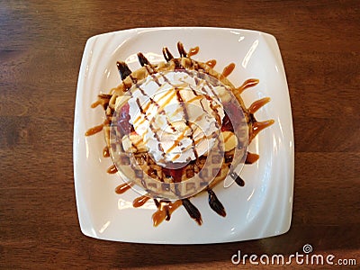 Banana split with whip cream, ice cream, strawberry jam and syrup on top of waffle Stock Photo