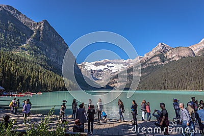 Banff, Canada - Ago 14th 2017 - Group of tourists in front of Lake Moraine in the early morning. Blue sky, mountains in the backgr Editorial Stock Photo