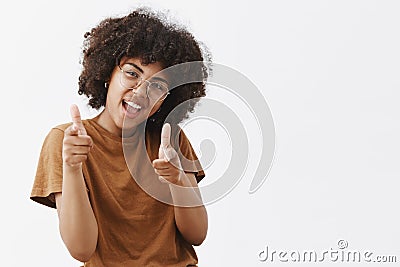 Bang bang you killed. Cool and carefree playful dark-skinned female student in transparent glasses and brown t-shirt Stock Photo