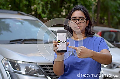 Bangalore, India, 2020. Girl showing Ola app on her mobile phone screen while standing in front of her fleet of cars. Its an Editorial Stock Photo