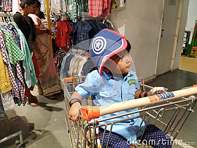 Indian Blue Shirt Wear little Kid in a Big Bazaar Sitting in a Trolley with Cap Editorial Stock Photo