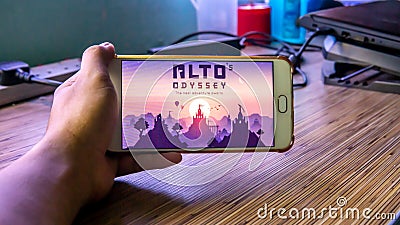 Hands holding a smartphone with Alto's Odyssey game on display screen Editorial Stock Photo