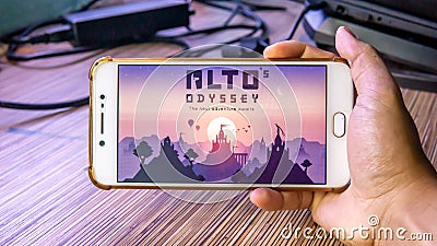 Hands holding a smartphone with Alto's Odyssey game on display screen Editorial Stock Photo